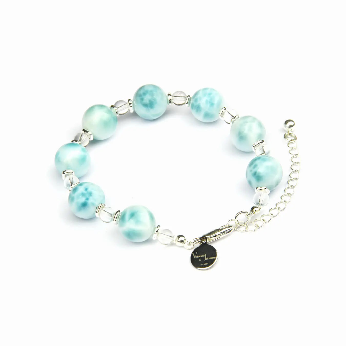 A beaded bracelet with light blue marbled beads, silver-toned metal links, a silver chain extender, and a small round black charm with gold lettering, shown on a plain white background.