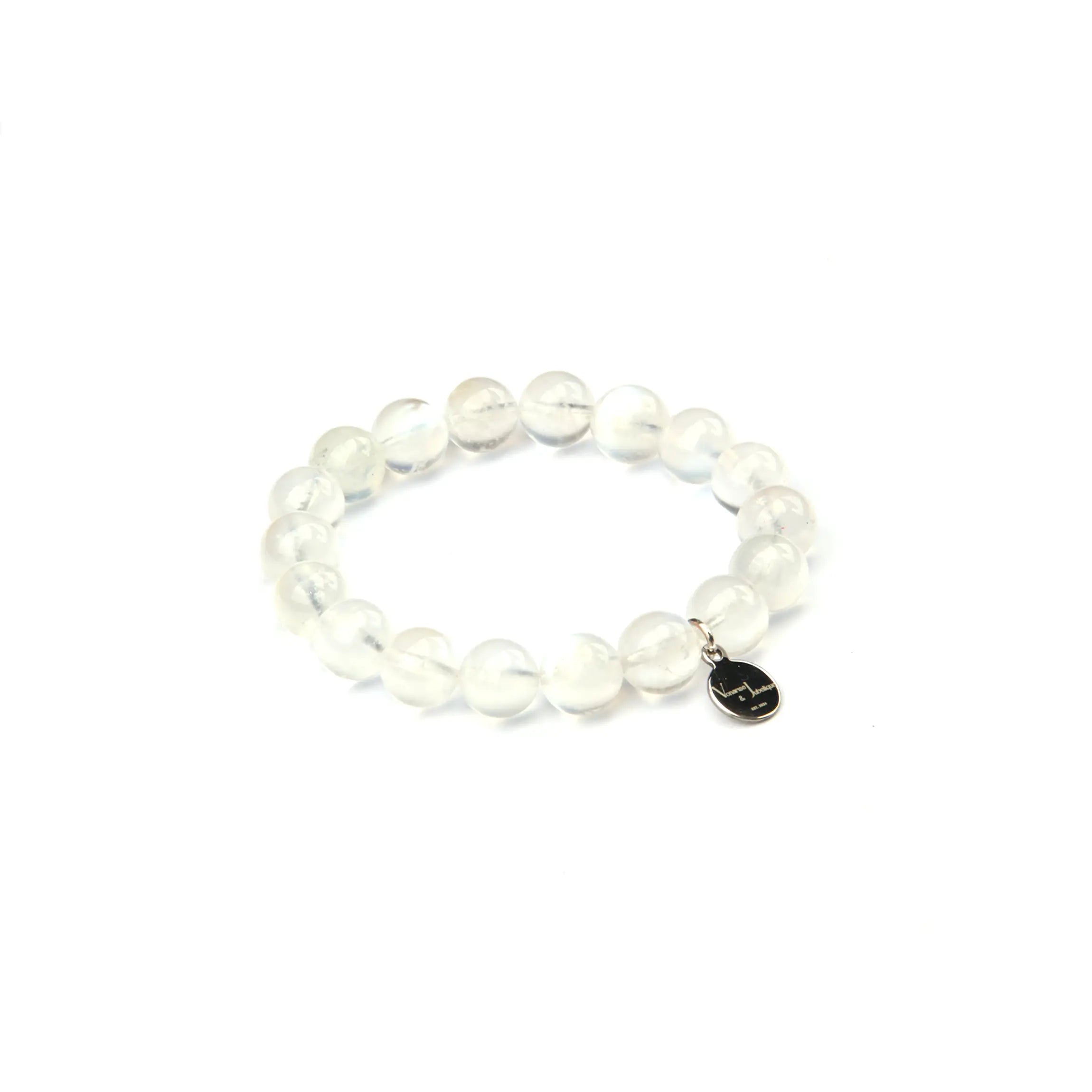 A beaded stretch bracelet made of clear, round stone beads with a small black oval charm featuring a white line drawing, shown on a plain white background.