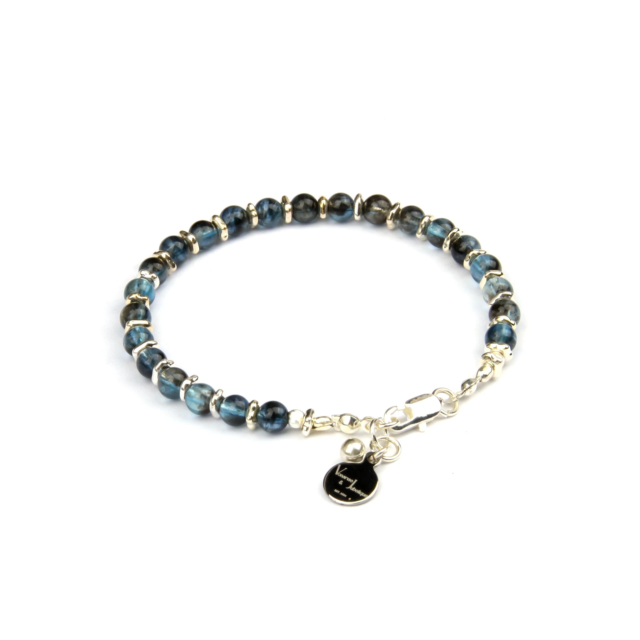 A beaded bracelet featuring dark blue-green labradorite beads separated by small gold spacer rings, with a gold-tone lobster clasp and a dangling black heart charm engraved with a lightning bolt.