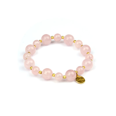 A pink gemstone beaded bracelet with small gold spacer beads and a small gold heart charm, displayed on a clean white background.